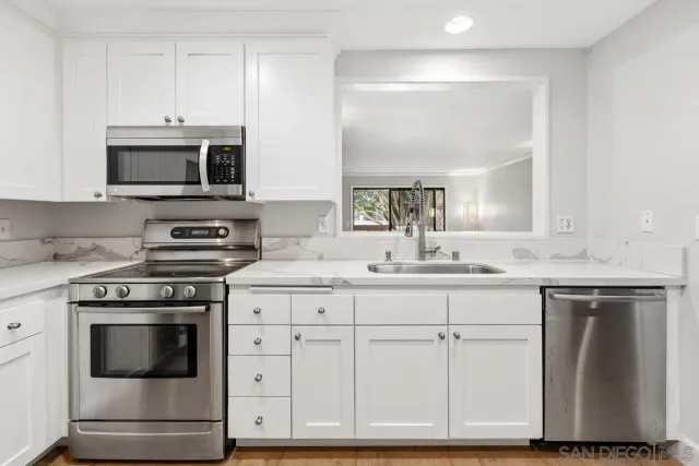 a kitchen with white cabinets and appliances