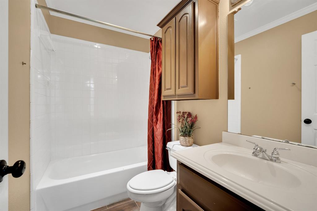 1907 Timber Ridge Court Cedar Hill, TX 75104 - Photo 24 of 30 Bathroom featuring a white tub and shower combination with subway tile surround, a single vanity with an integrated sink and chrome faucet, and wood-finish flooring