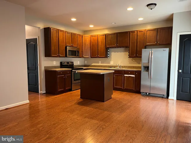 a kitchen with stainless steel appliances granite countertop wooden cabinets a refrigerator a stove a sink and a microwave