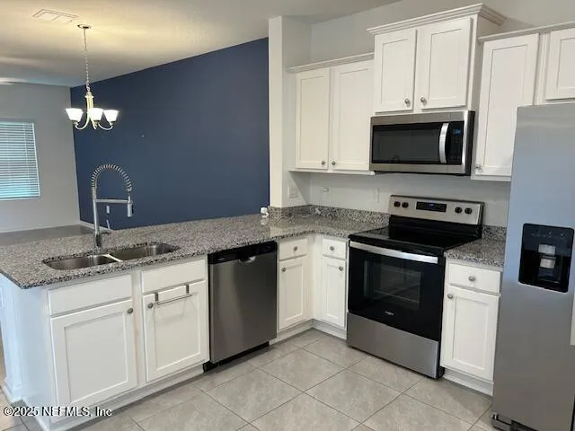 a view of a kitchen with kitchen island granite countertop stainless steel appliances cabinets a sink and a counter top space