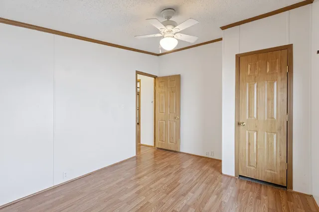 an empty room with wooden floor and a ceiling fan