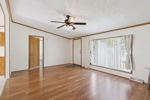 a view of empty room with wooden floor and fan