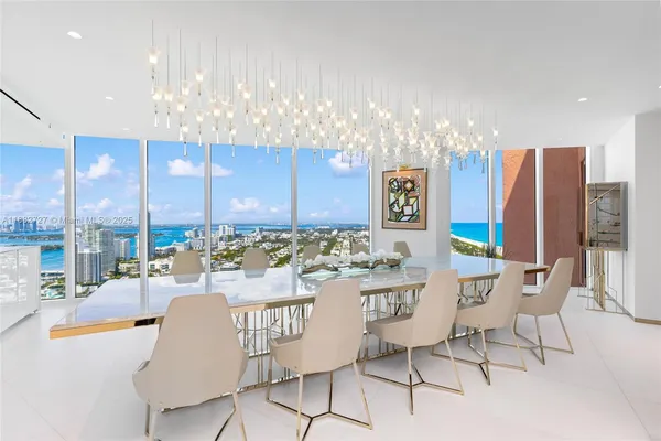 a view of a dining room with furniture a chandelier and kitchen view