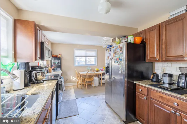 a kitchen with stainless steel appliances granite countertop a refrigerator a sink dishwasher a stove and a dining table with wooden floor