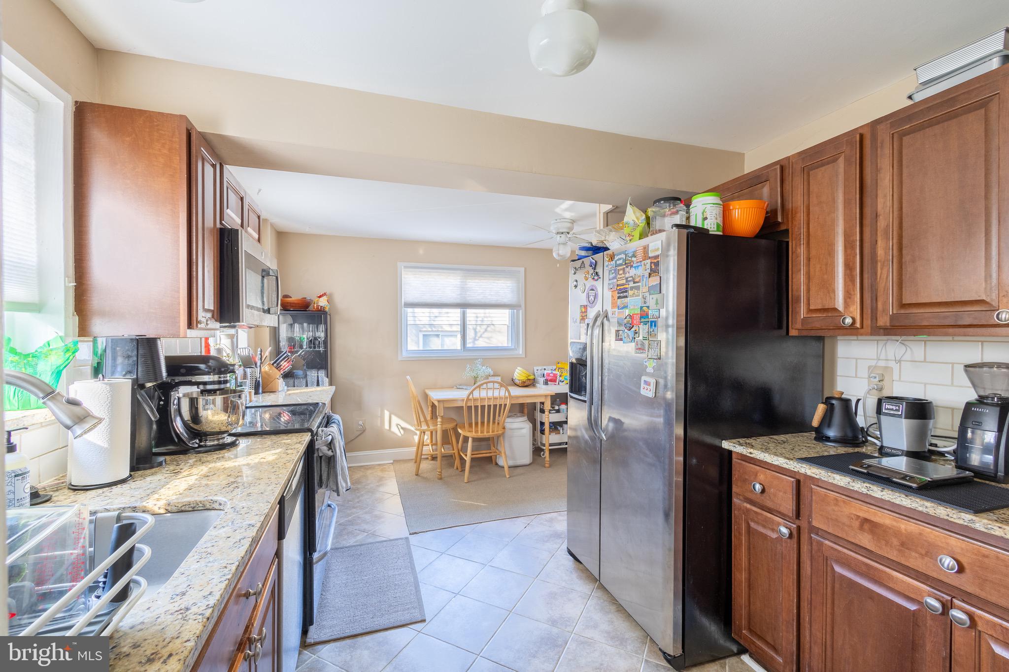 10611 Maple Street Fairfax, VA 22030 - Photo 8 of 20 a kitchen with stainless steel appliances granite countertop a refrigerator a sink dishwasher a stove and a dining table with wooden floor