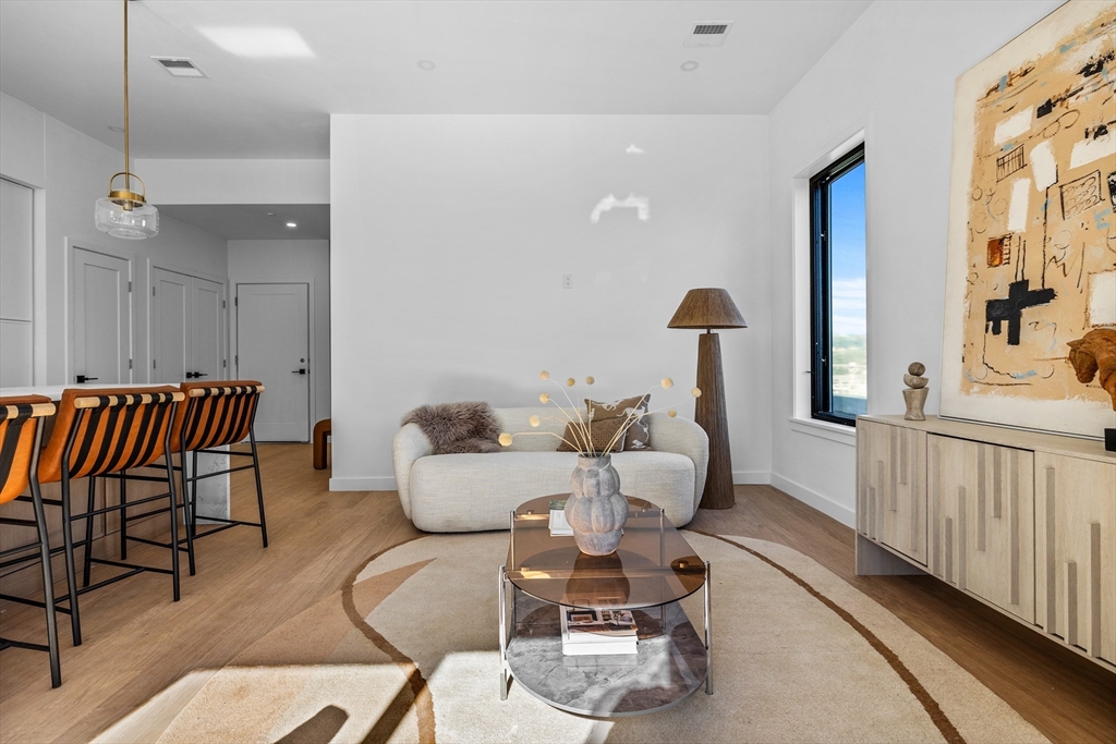 125 Addison Street, Unit 206 Boston, MA 02128 - Photo 6 of 17 a living room with furniture a rug and painting on the wall