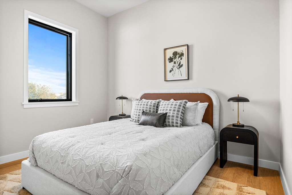 125 Addison Street, Unit 206 Boston, MA 02128 - Photo 10 of 17 a bedroom with a bed and a lamp on table