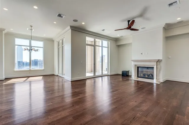 an empty room with wooden floor fireplace and windows