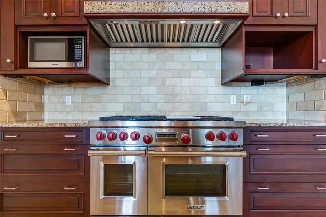 a kitchen with stainless steel appliances granite countertop stove top oven and cabinets