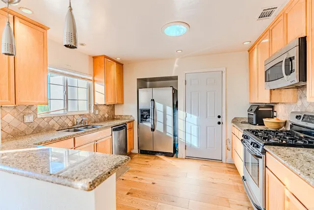 a kitchen with stainless steel appliances granite countertop a stove a refrigerator and a sink