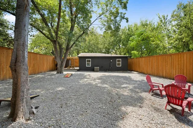 a view of a backyard with a table and chairs and a large tree