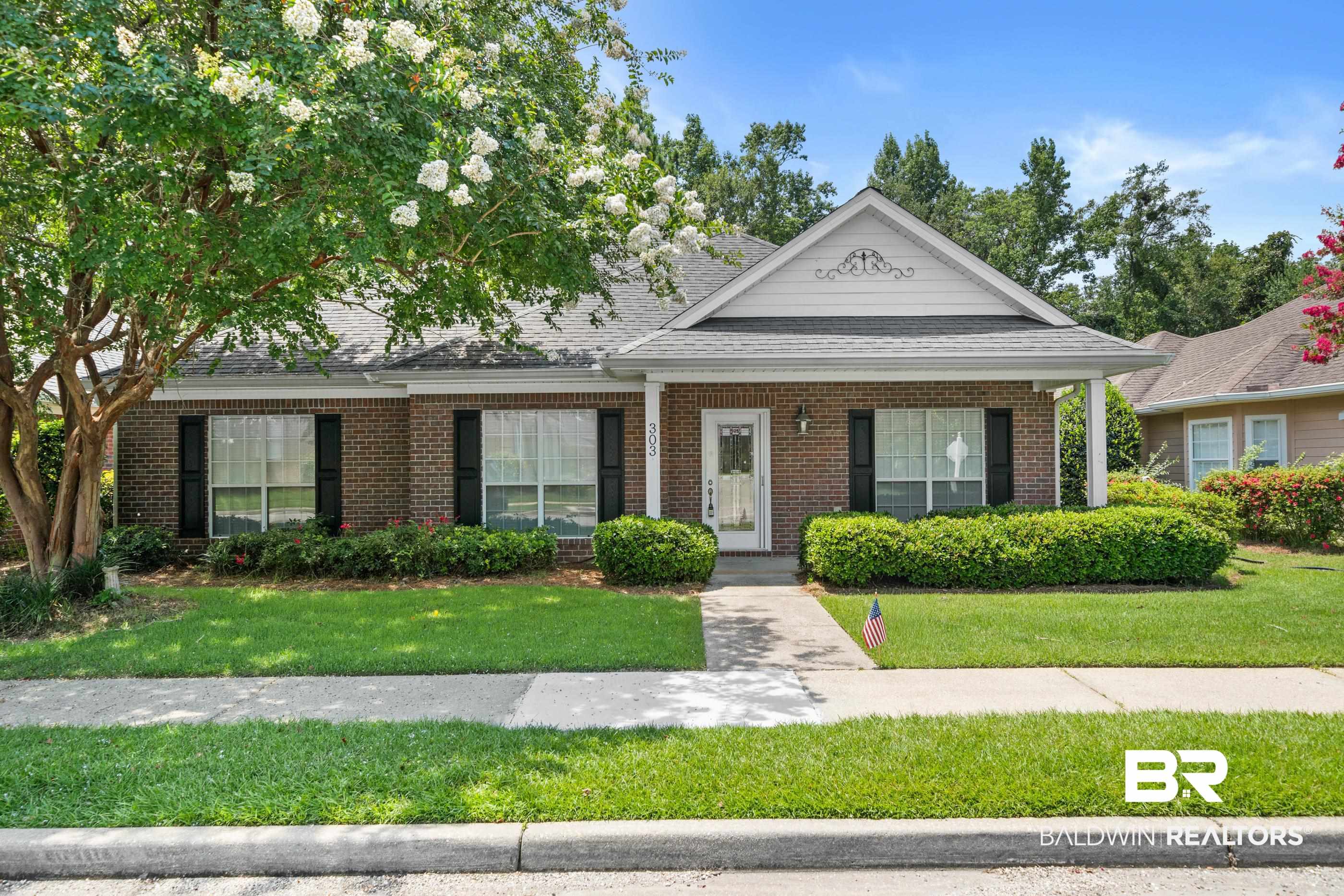 303 Savannah Circle Foley, AL 36535 - Photo 1 of 34 Brick facade ranch-style home featuring a covered front porch, decorative gable, and manicured landscaping