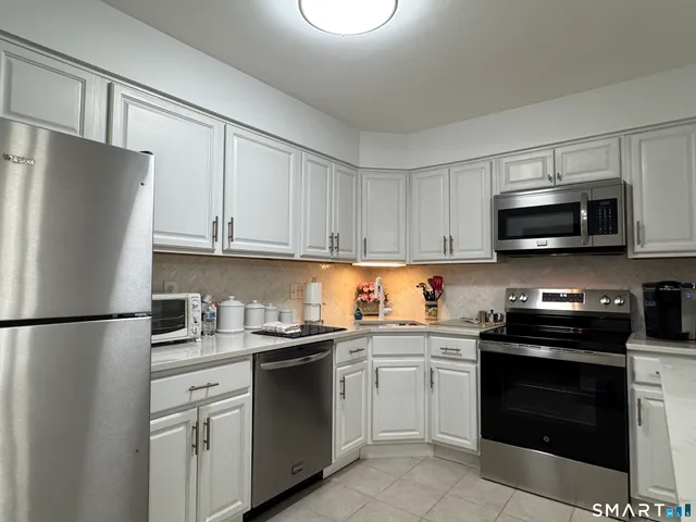 a kitchen with stainless steel appliances granite countertop a refrigerator stove a sink and a microwave