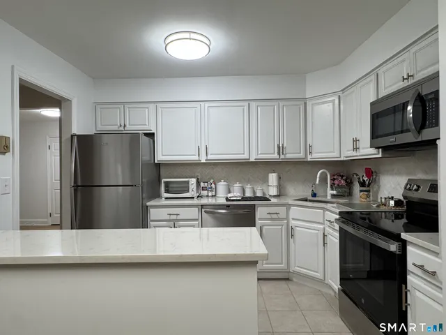 a kitchen with stainless steel appliances granite countertop grey cabinets a stove a sink and dishwasher
