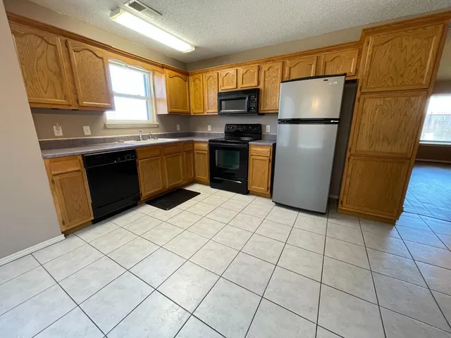 a kitchen with a refrigerator a stove a sink a microwave and cabinets