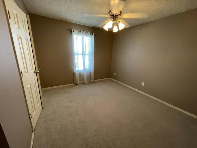 an empty room with windows and fan