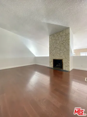 a view of empty room with a fireplace and wooden floor