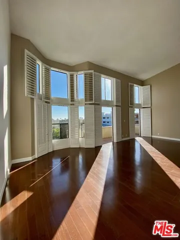 a view of a big room with wooden floor and windows