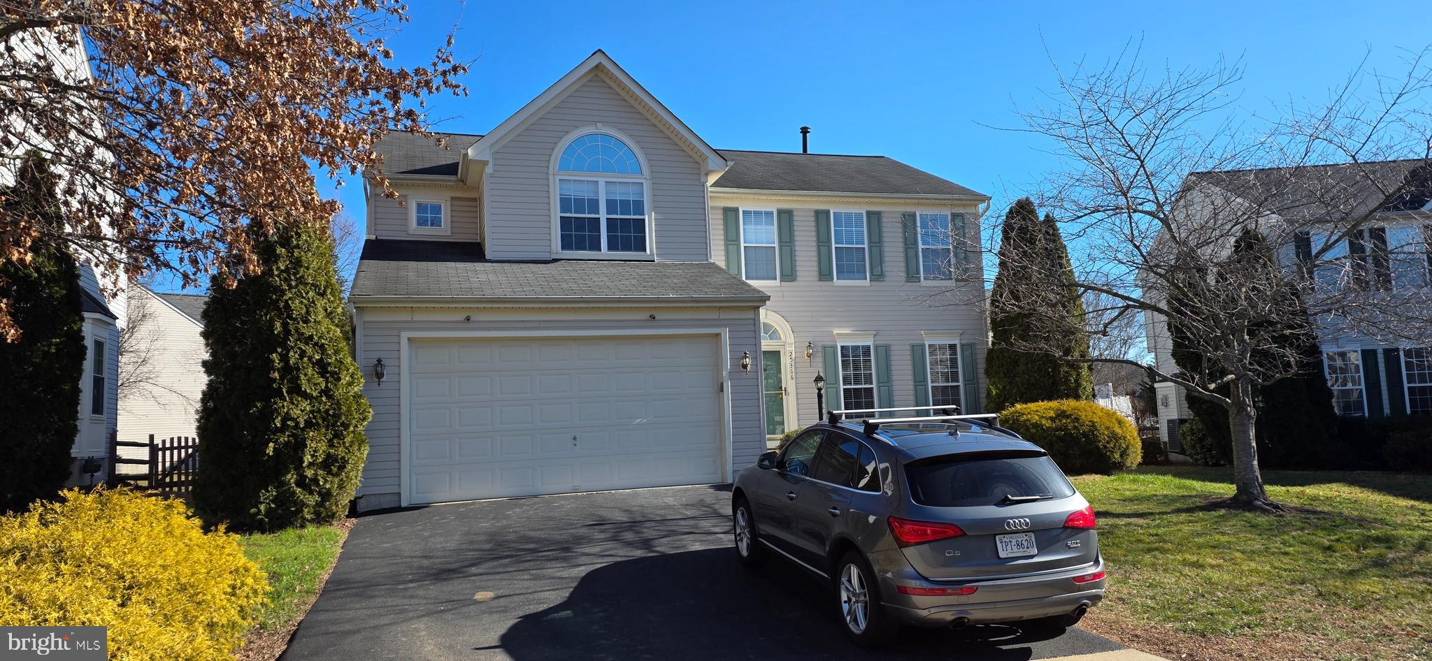 a car parked in front of a brick house with a small yard