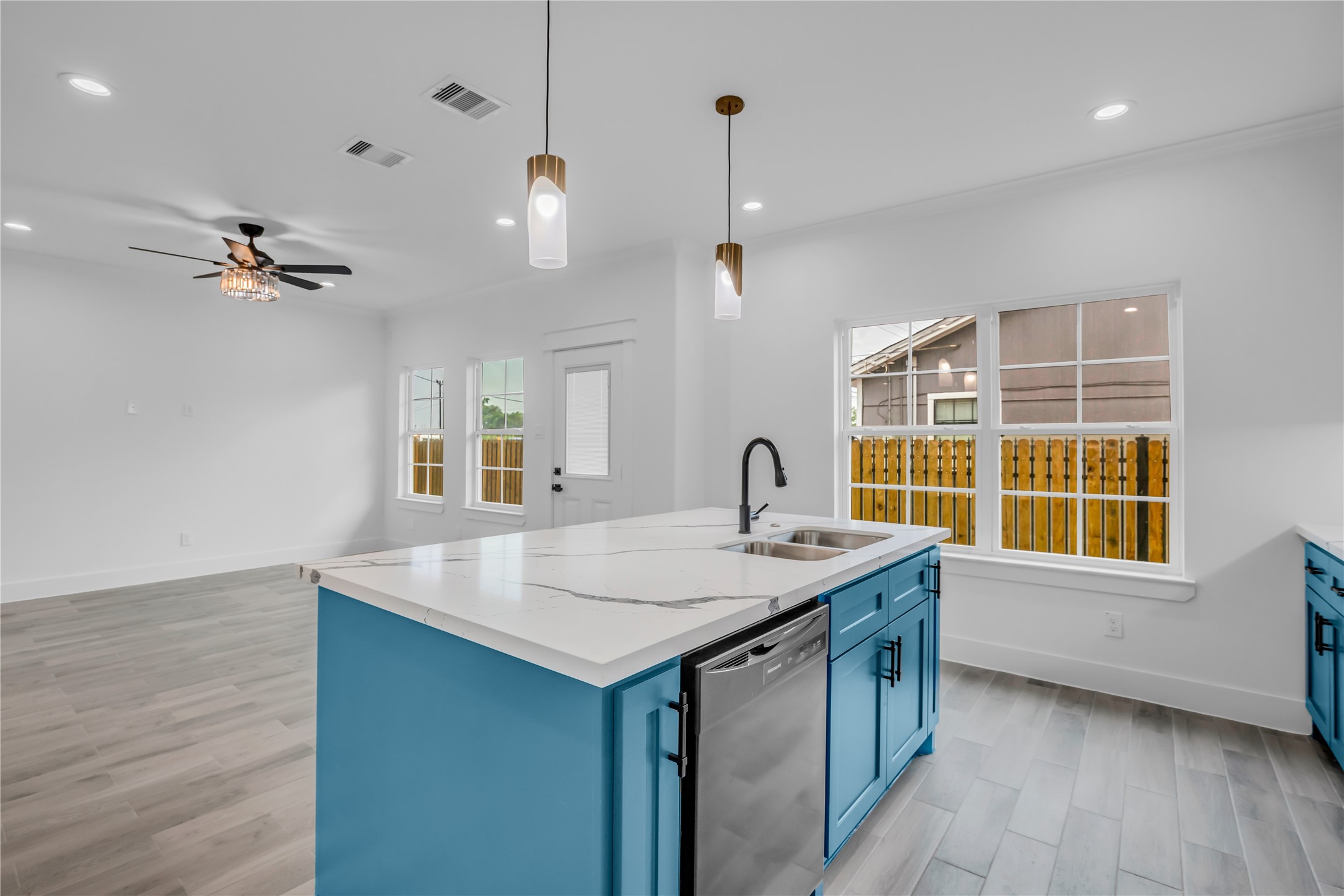 3168 Golfcrest Houston, TX 77087 - Photo 9 of 30 Discover a bright, open-concept kitchen and living room featuring sleek blue cabinetry, modern fixtures, and ample natural light, perfect for stylish living and entertaining.