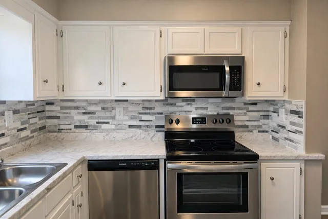 a kitchen with granite countertop white cabinets and stainless steel appliances