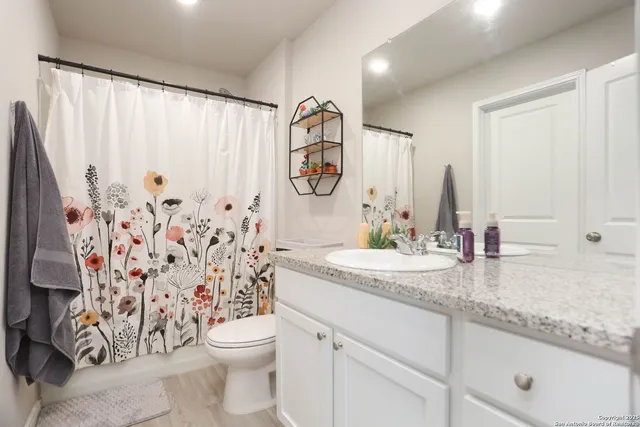 a bathroom with a granite countertop sink a toilet and a shower