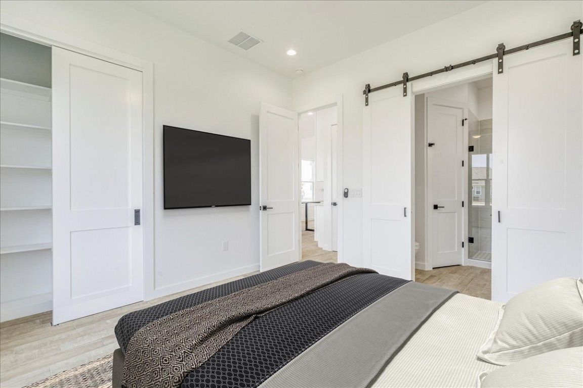 126 Lourdes Court, Unit B Dripping Springs, TX 78620 - Photo 11 of 19 a bedroom with a bed and a flat tv screen on wall