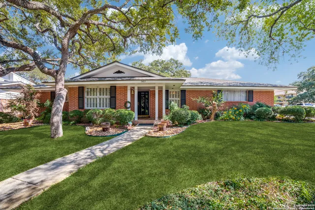 a front view of a house with a yard and potted plants