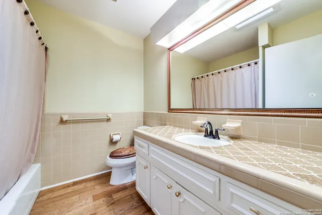 a bathroom with a granite countertop sink a large mirror and a toilet