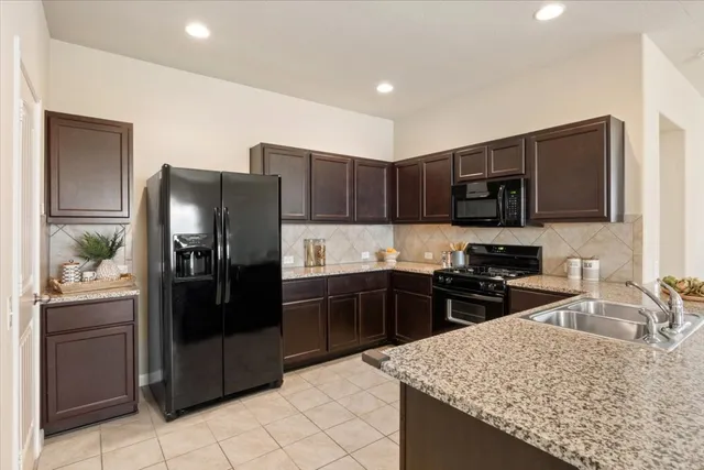 a kitchen with granite countertop wooden cabinets a refrigerator and a sink