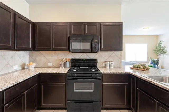a kitchen with granite countertop stainless steel appliances a stove sink and microwave