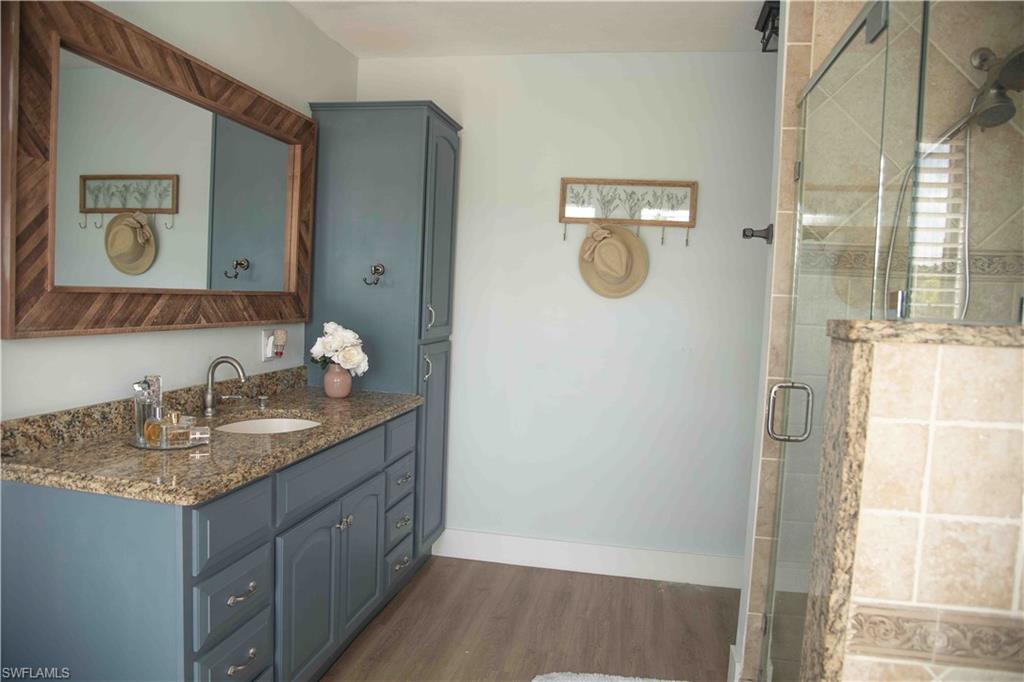 3220 63rd Street Southwest Naples, FL 34105 - Photo 26 of 36 Bathroom featuring wood finished floors, vanity, and a shower stall