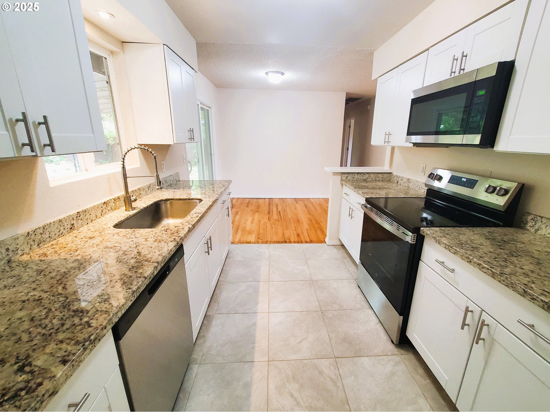 13050 Southeast Morrison Street Portland, OR 97233 - Photo 8 of 21 a large kitchen with granite countertop a sink and a stove top oven with wooden floor