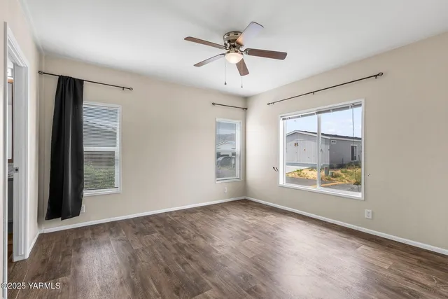 a view of an empty room with a window and wooden floor