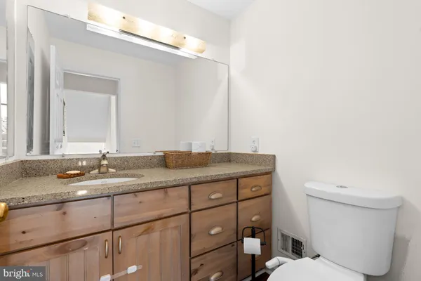 a bathroom with a granite countertop toilet sink and mirror