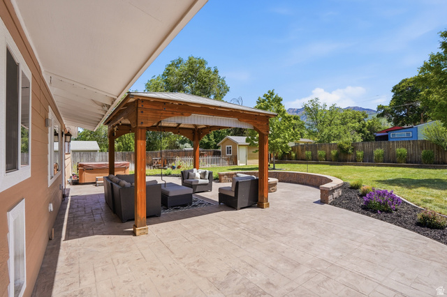 6889 South Village Road Salt Lake City, UT 84121 - Photo 30 of 44 Expansive stamped concrete patio featuring a wood gazebo with a metal roof, a built-in stone retaining wall, and a fire pit