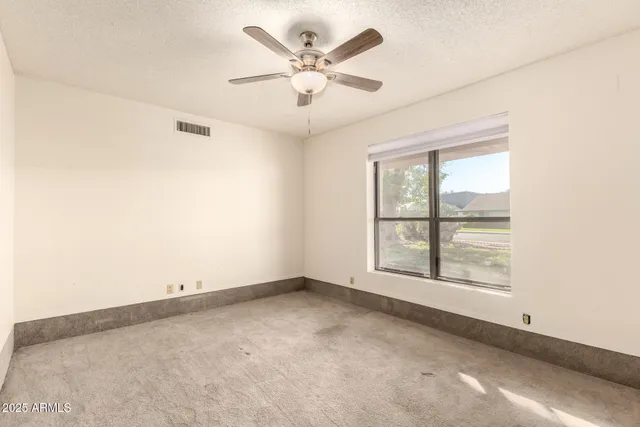 an empty room with windows and fan