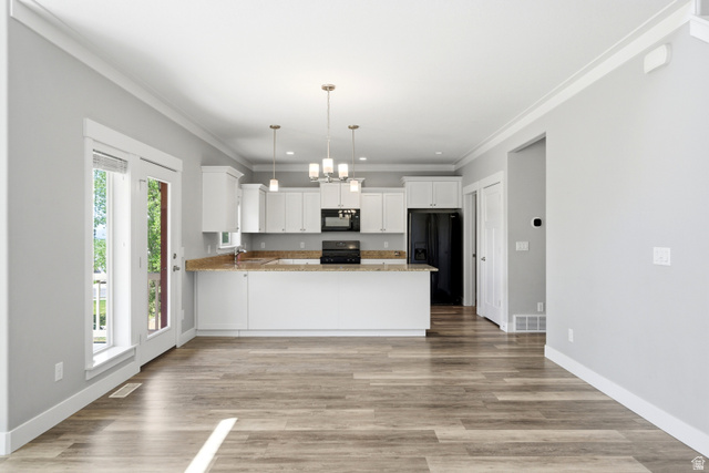 1614 Aspen Loop Provo, UT 84606 - Photo 12 of 47 Open-concept living space with wood-finish flooring, white cabinetry, a built-in kitchen island with stone-finish countertops, pendant lighting, and double glass-paneled doors leading to an outdoor area