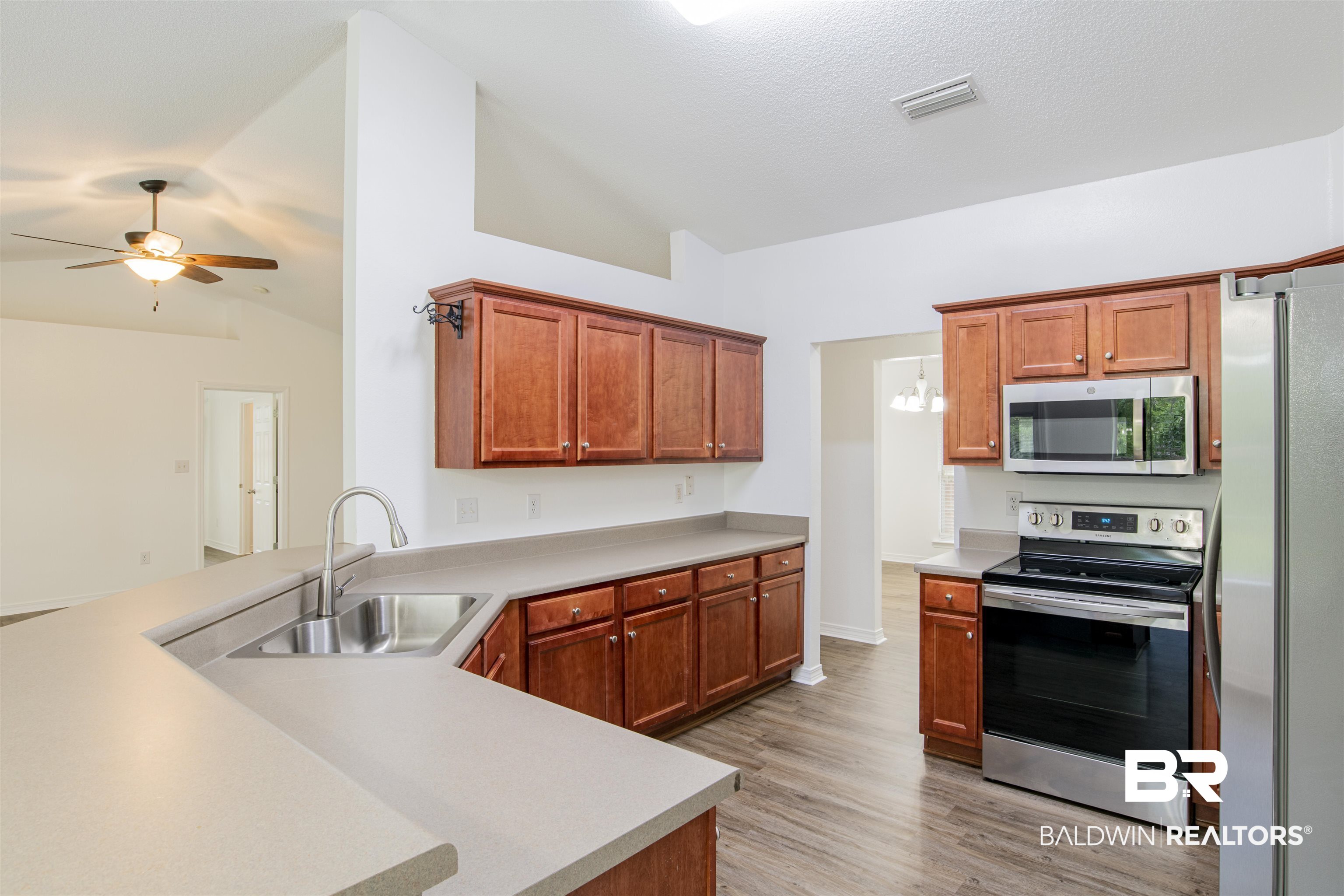 165 Pemberton Loop Fairhope, AL 36532 - Photo 13 of 25 Kitchen with a sink, light wood finished floors, lofted ceiling, stainless steel appliances, and visible vents