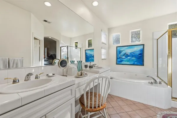 a bathroom with a bathtub double sink and a mirror