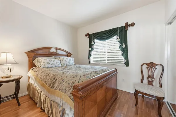 a bedroom with a bed and a chair with the wooden floor
