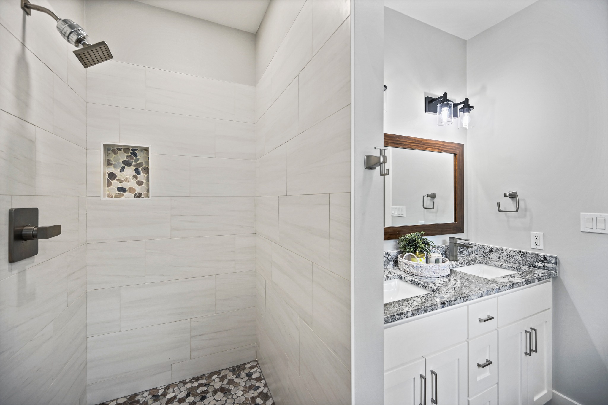 231 North Rainbow Ranch Road Wimberley, TX 78676 - Photo 20 of 40 Double vanity and a modern shower with stone accents elevate this well-appointed bathroom.