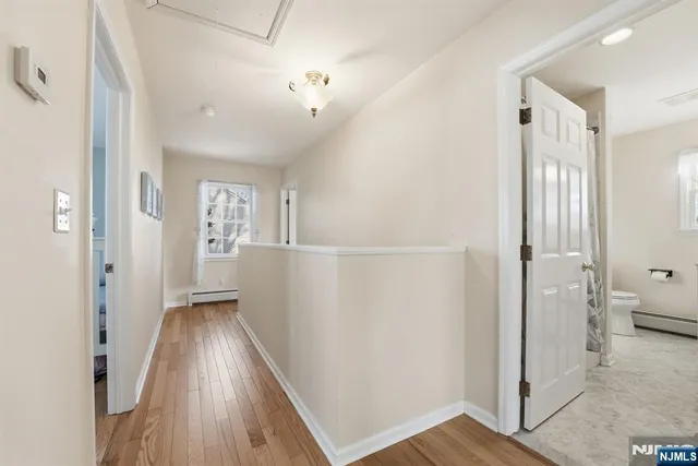 a view of a hallway with wooden floor and a bathroom
