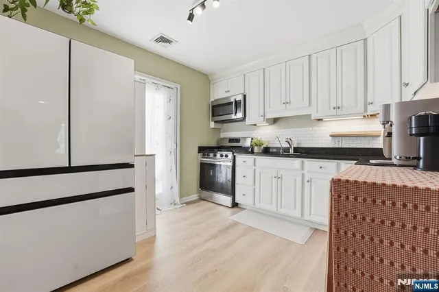 a kitchen with granite countertop white cabinets and stainless steel appliances
