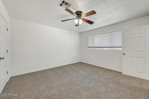 an empty room with a window and a fan
