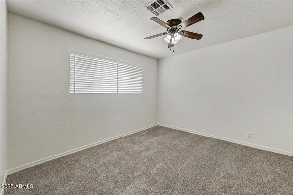 an empty room with a window and a fan