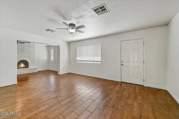 an empty room with wooden floor chandelier fan and windows