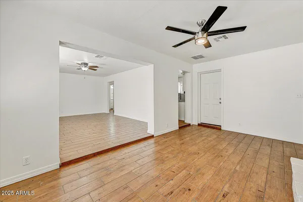 a view of a livingroom with wooden floor a ceiling fan and windows