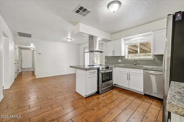 a kitchen with stainless steel appliances granite countertop a stove a refrigerator and a sink