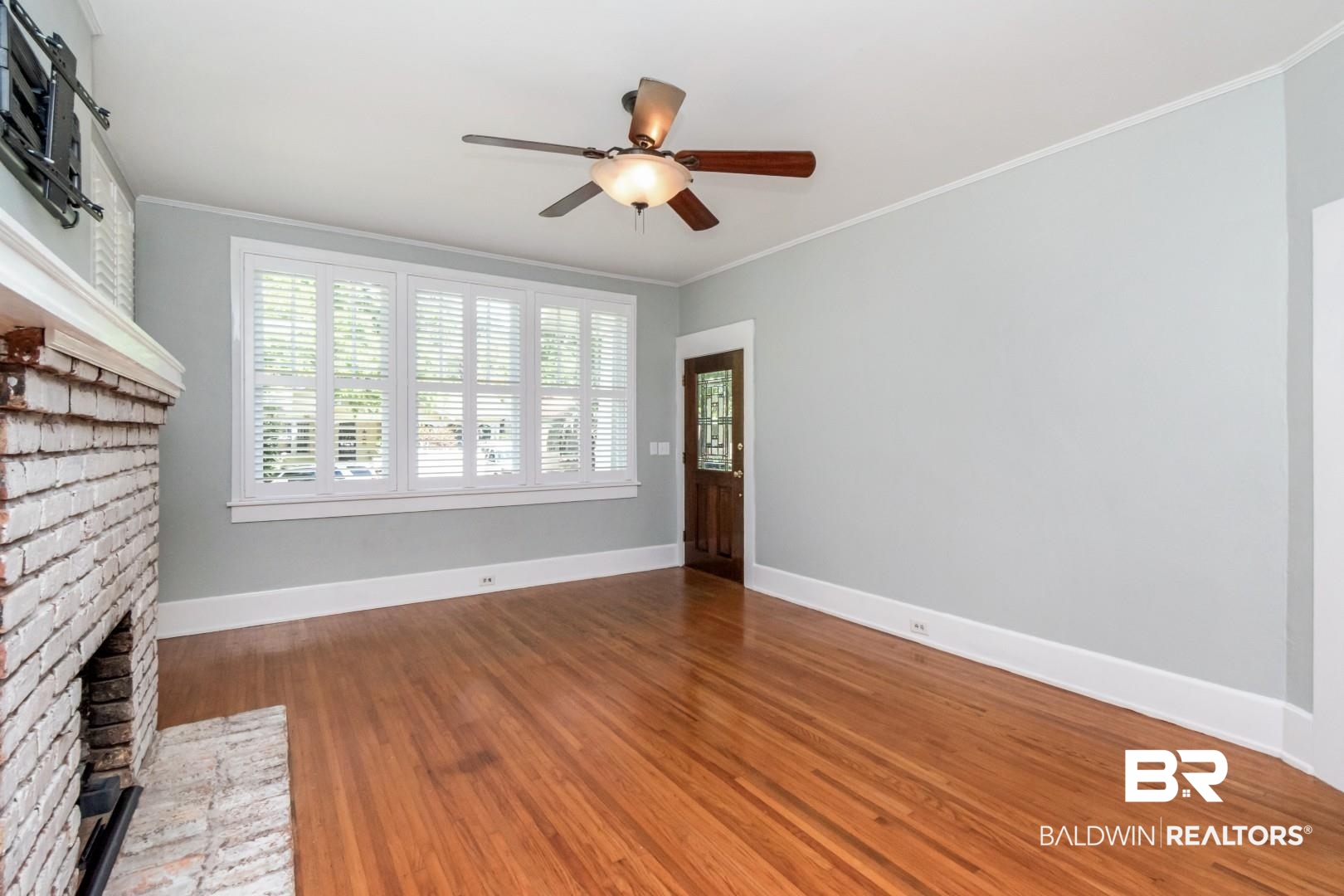 10 Macy Place Mobile, AL 36604 - Photo 8 of 43 Unfurnished living room with dark wood-style flooring, ceiling fan, ornamental molding, and a brick fireplace